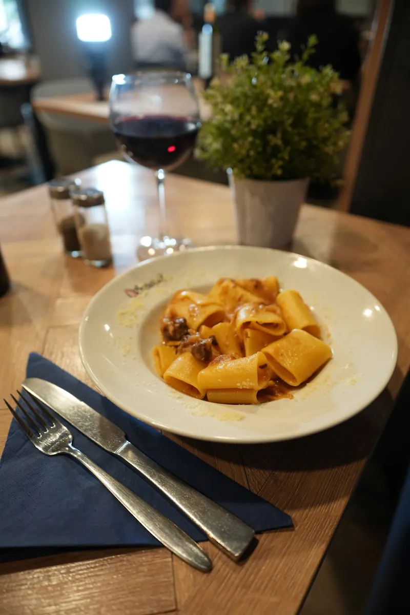 Un piatto di paccheri e un calice di rosso, in sala
